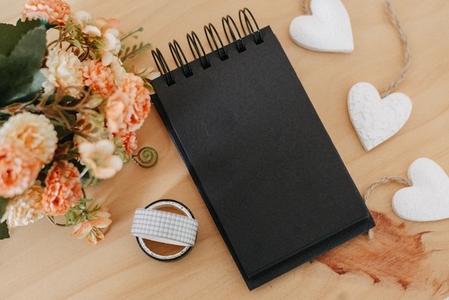notebook with black sheets with copy space  bouquet of flowers and a white heart
