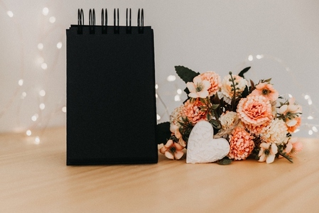 notebook with black sheets with copy space  a bouquet of flowers and a white heart