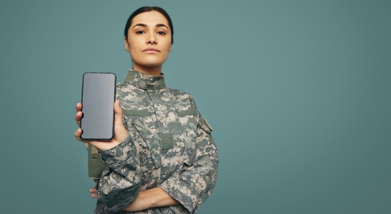 Soldier displaying a smartphone screen in a studio