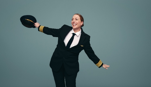 Happy female pilot mimicking an airplane in a studio