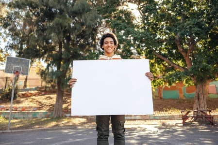 Smiling teenage activist displaying a blank banner outdoors