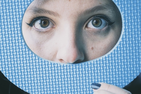 Close up of young womans eyes and her face covered by a blue ci