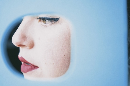 Pretty young woman face behind a blue circle