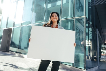 Female business activist holding a blank placard outside her workplace