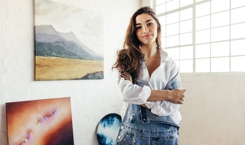 Cheerful painter standing in front of her artwork