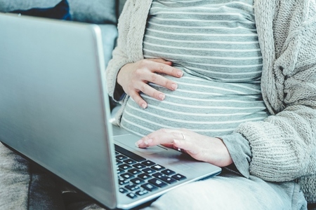 Young pregnant woman working at home with her laptop