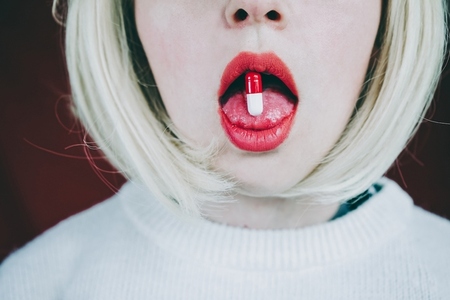 Conceptual image about drug addict with a pill in a young woman