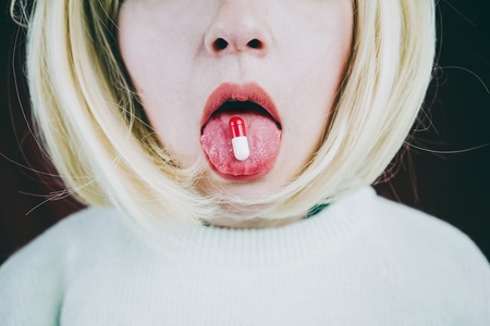 Conceptual image about drug addict with a pill in a young woman
