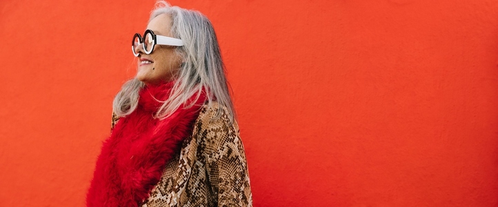 Happy grey haired woman smiling cheerfully against a red background