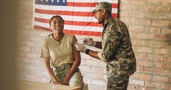 Happy servicewoman receiving a vaccine in the military hospital