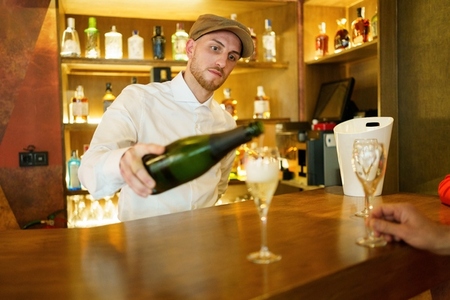Barman pouring drink in glasses in bar