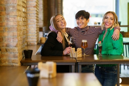 Cheerful girlfriends hugging during party in bar