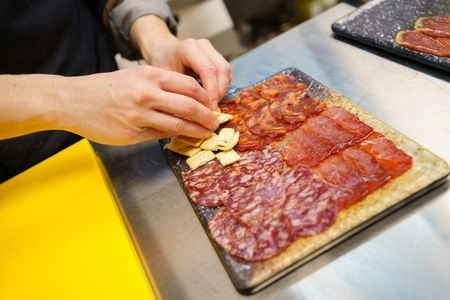 Unrecognizable chef preparing a plate of Iberian cured meats platter