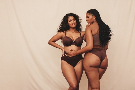 Two young women embracing their natural bodies while wearing brown underwear