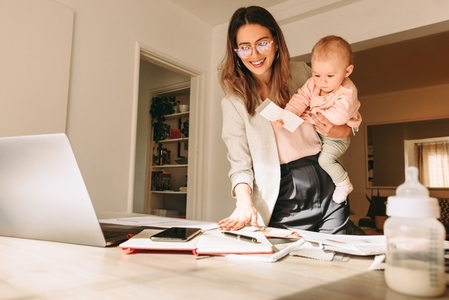 Mom holding her baby while working in her home office