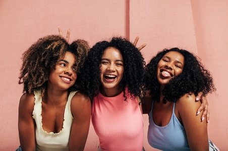 Portrait of three laughing females with curly hair  Happy women having fun together looking at camera