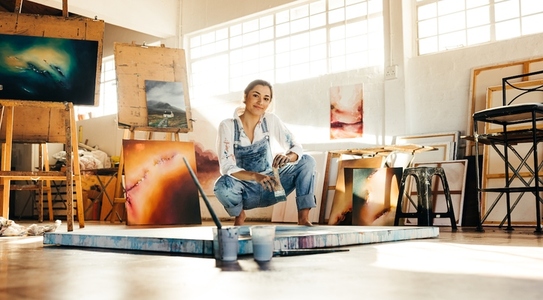 Creative painter squatting close to her painting