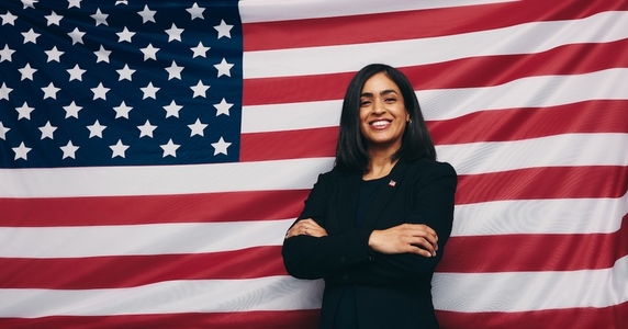 Cheerful young congresswoman smiling against an American flag