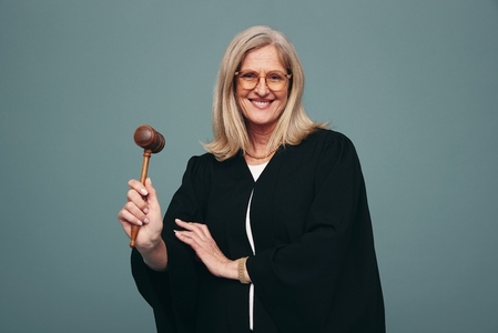Cheerful mature judge holding up a gavel in a studio