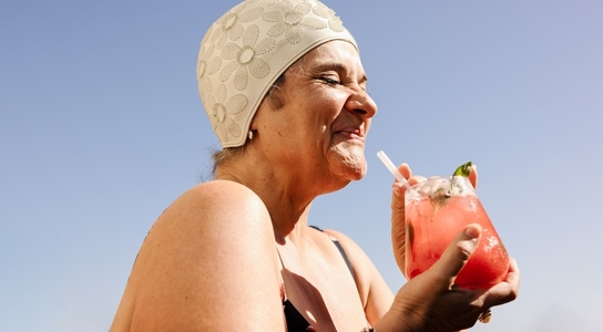 Mature woman enjoying a tiki cocktail in the summer