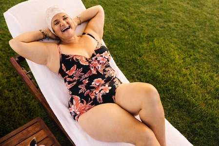 Cheerful elderly woman relaxing on a lounger at a spa resort