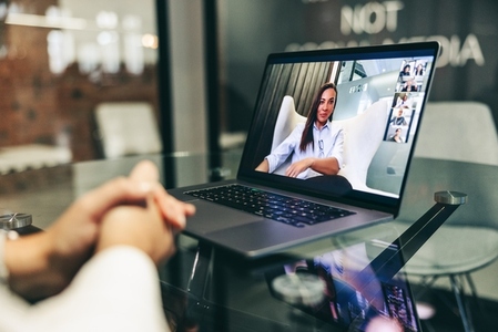 Anonymous businesswoman attending a virtual meeting in a modern office