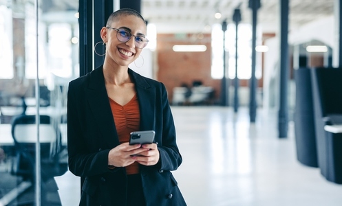 Confident businesswoman smiling while holding a smartphone