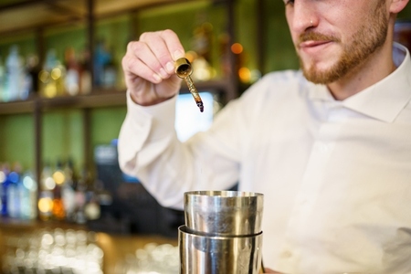 Barman adding bitters to cocktail in a modern pub