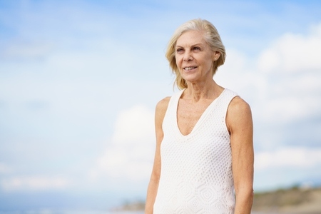 Mature woman walking on the beach  Elderly female standing at a seaside location