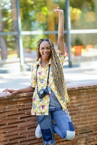 Black woman with African braids  raising her arm in joy  Girl holding a camera