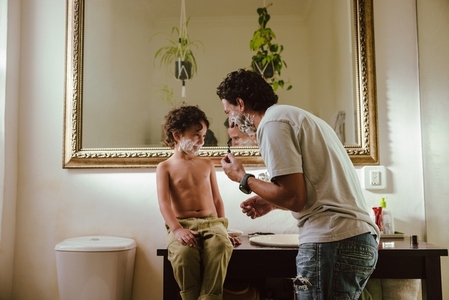 Young father and son having fun with shaving cream