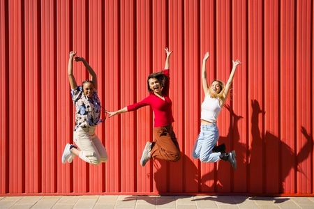 Delighted women jumping near wall
