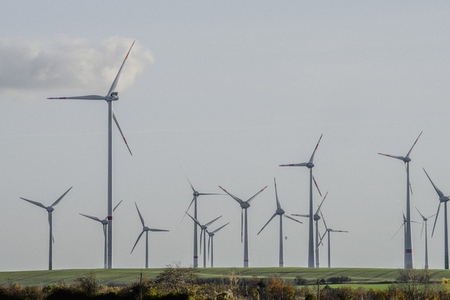 Wind turbine farm in sunny rural field against blue sky Germany