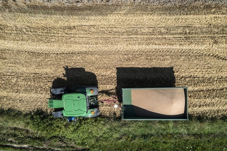 Aerial drone POV tractor and trailer in sunny field