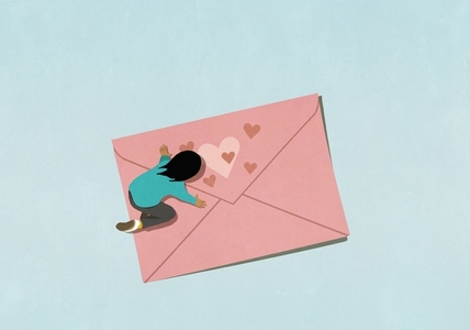Woman kneeling over pink envelope with hearts