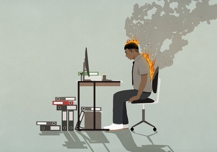 Businessman on fire working at computer at office desk