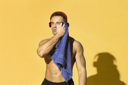 Athletic man wiping sweat from face with towel