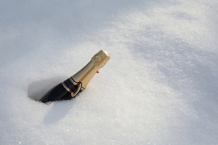 Bottle of champagne with gold foil buried in snow