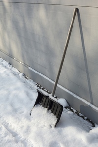 Snow shovel leaning against winter wall