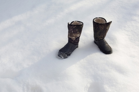 Camouflage winter boots in snow