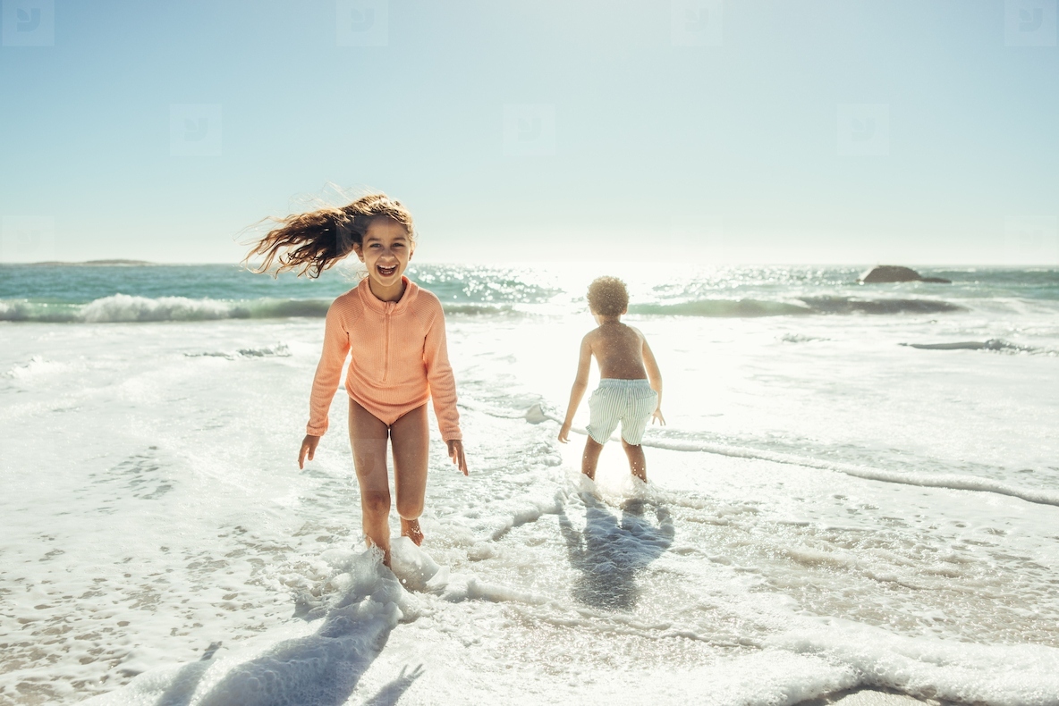 Active little girl playing in sea water at the beach