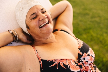Ecstatic senior woman relaxing on a lounger in swimwear
