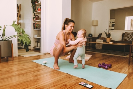 Yogi mom lifting her baby on an exercise mat