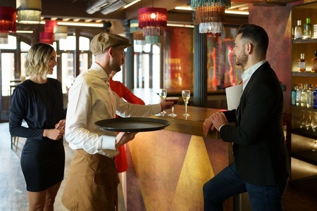 Barman serving cocktail on counter for clients