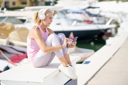 Mature sporty woman taking a break to check a fitness app on her smartphone
