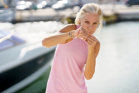 Mature woman doing shadow boxing outdoors  Senior female doing sport in a coastal port
