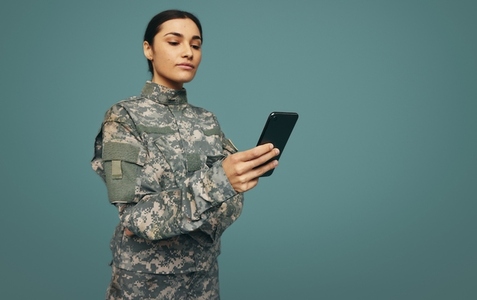 Military servicewoman using a smartphone in a studio