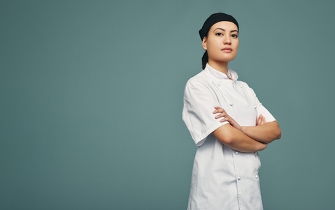 Culinary chef standing with her arms crossed in a studio