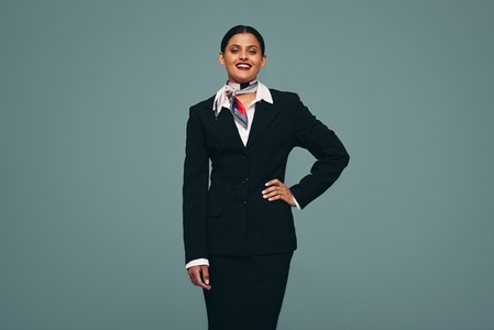 Confident air hostess smiling at the camera in a studio