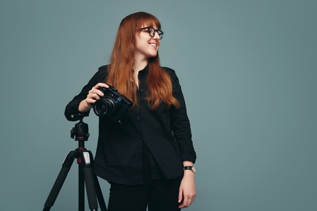 Professional photographer standing next to her tripod in a studi